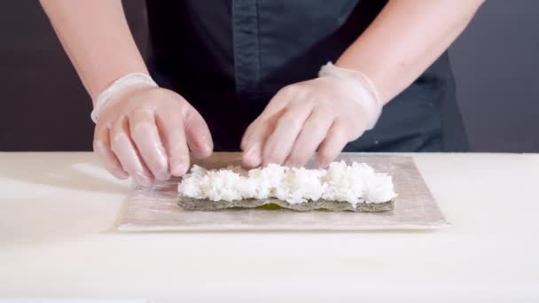 Zblízka šéfkuchař mužské ruce v rukavicích vaření sushi rolls v kuchyni. — Stock video