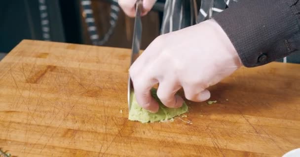 Крупним планом знімок рук шеф-кухаря в рукавичках, що рубають стиглий авокадо на дерев'яній дошці — стокове відео