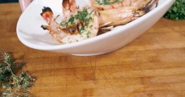 Beyaz bir tabakta otlu ve baharatlı büyük ızgara karides yakın çekim