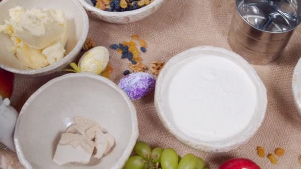 Primer plano de los ingredientes para hacer pastel de Pascua y huevos decorados en un lienzo. Preparación para las vacaciones de Pascua. — Vídeo de stock