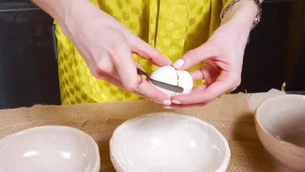 Nærmer seg hunnens hender og deler eggeskall og eggeplommer og hvite i forskjellige skåler. Kokekjeks eller deig. – stockvideo