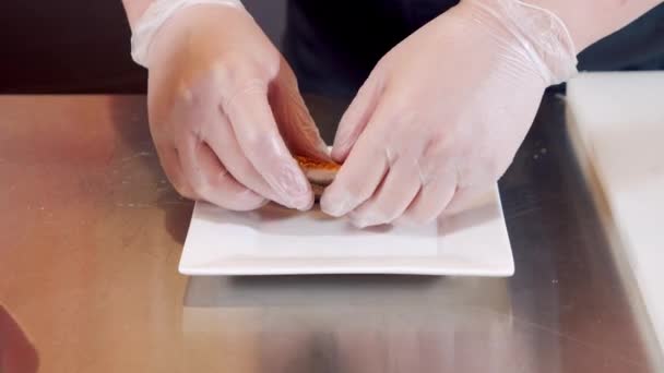 Gros plan des mains masculines du chef dans des gants préparant un délicieux apéritif avec des morceaux de thon fumé sur une assiette — Video