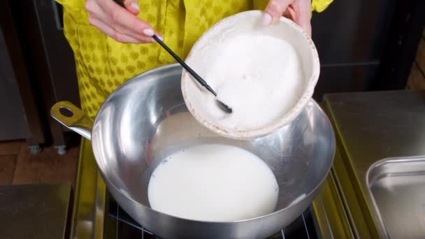 Close-up van vrouwelijke handen die suiker in warme melk doen terwijl ze deeg maken voor muffins in de keuken. — Stockvideo