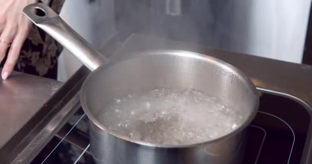 电炉上装有开水的勺的特写。厨房里做饭. — 图库视频影像