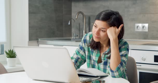 Giovane donna stanca di lavorare sul computer portatile e bere caffè sensazione di sonnolenza in cucina a casa. — Video Stock