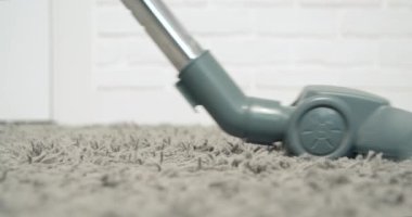 Elektrikli süpürgeyi kapat oturma odasındaki toz ve gri halının kalıntılarını temizle..