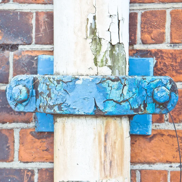 Close up of a blue rusty clip on a white drainpipe — Stock Photo, Image