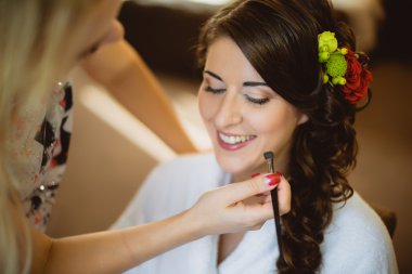 stylist maakt make-up bruid op de huwelijksdag