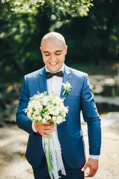 Der Bräutigam im blauen Anzug mit Schmetterling und Strauß — Stockfoto