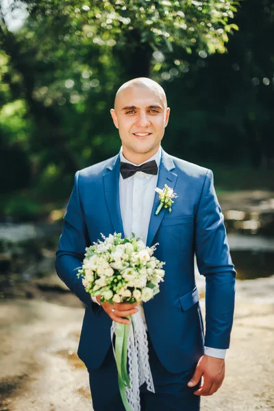 El novio en traje azul con mariposa y ramo —  Fotos de Stock