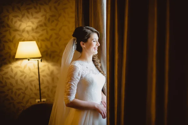 Braut im weißen Kleid steht am Fenster — Stockfoto