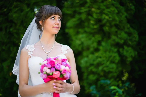 Noiva com um buquê de rosas no parque — Fotografia de Stock