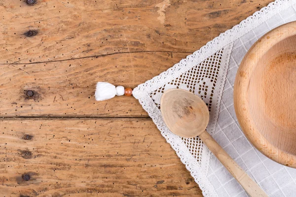 Tigela de madeira, colher e toalha de mesa em uma mesa de madeira rústica — Fotografia de Stock