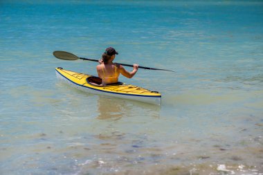 Genç bir kadın denizde kayak yapıyor.