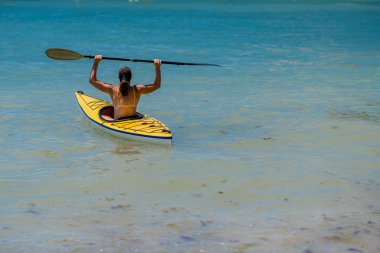 Genç bir kadın denizde kayak yapıyor.