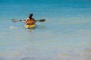Genç bir kadın denizde kayak yapıyor.