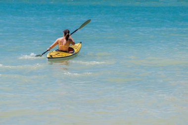 Genç bir kadın denizde kayak yapıyor.