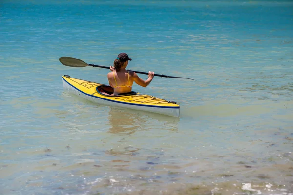 Genç bir kadın denizde kayak yapıyor.