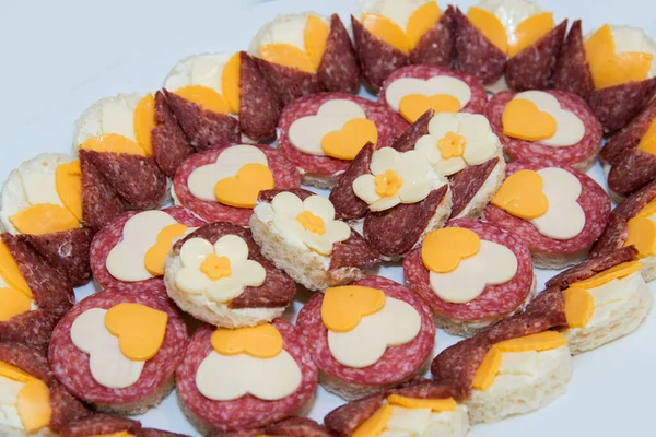 Catering food for the event - different types delicacies of meat and cheese arranged in a plate over light background - selective focus