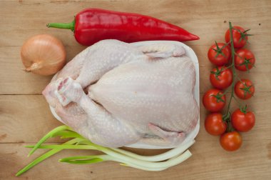 Çiğ tavuk ve sebzeler ahşap masada.