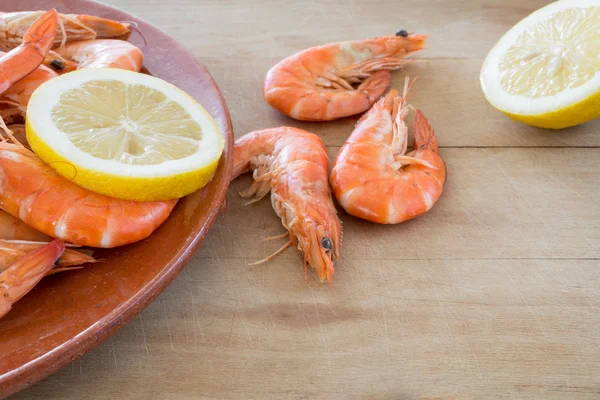 Gekookte garnalen met citroen gerangschikt aan boord van de keuken — Stockfoto
