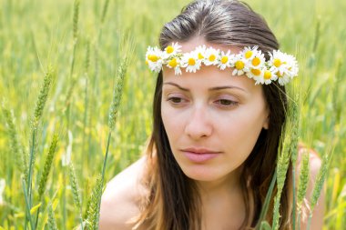 Bir çelenk çiçek alan arasında başında olan kadın