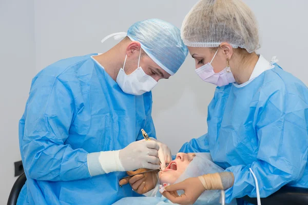 Стоматологи во время операции по установке имплантата — стоковое фото