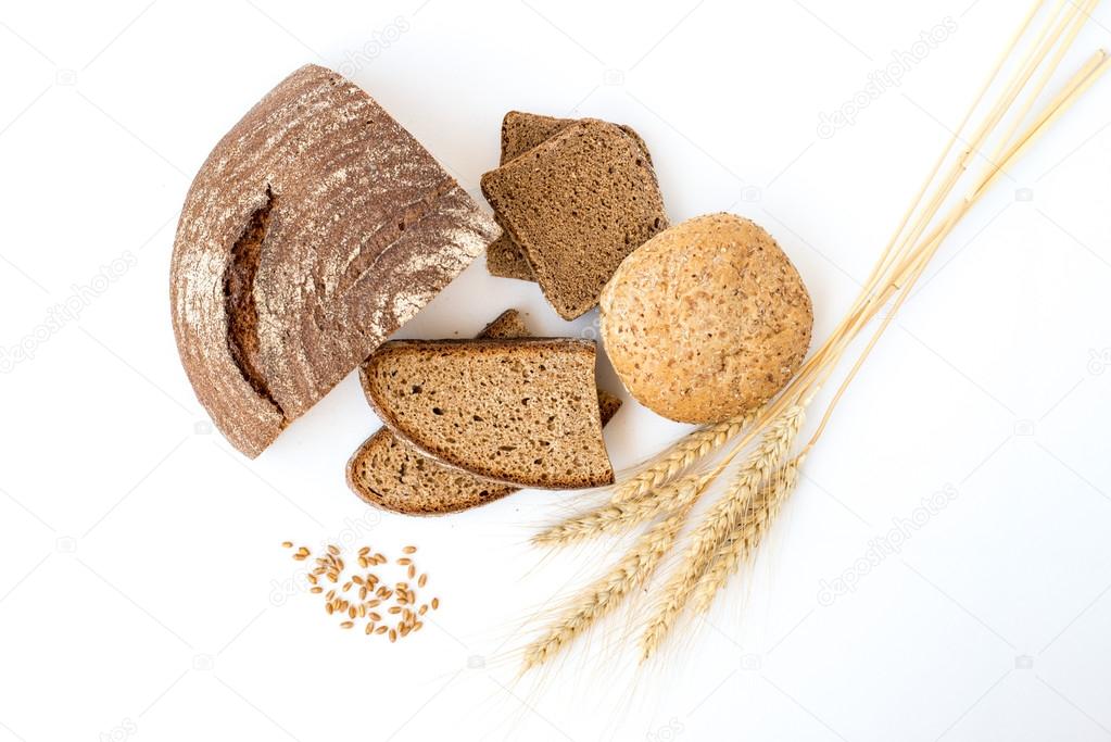 Variety of bread and stalks of wheat isolated on white