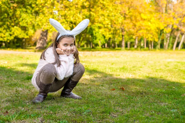 Adorable little girl outdoors at beautiful autumn day with rabbit ears on her head — Stock Photo, Image