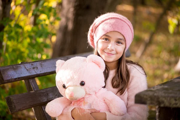 Adorable little girl outdoors at beautiful autumn day holding teddy bear — Stock Photo, Image