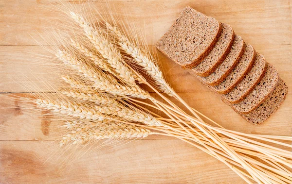 Rustic bread and wheat on an old vintage planked wood table — Stock Photo, Image