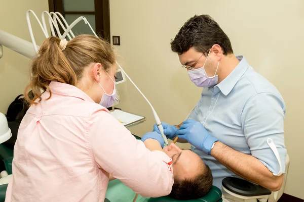 Dentista fazendo um tratamento odontológico em um paciente — Fotografia de Stock