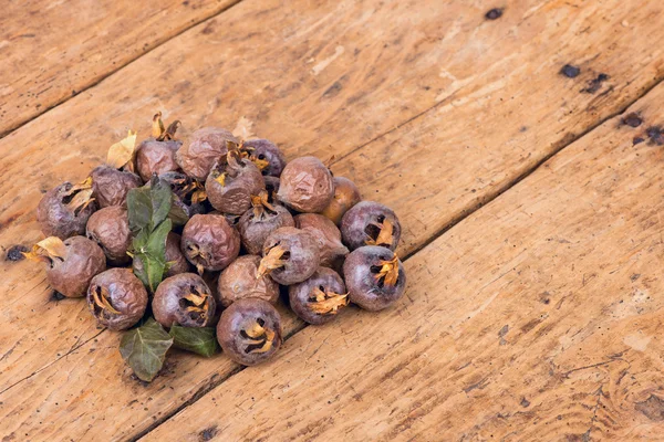 Eski ahşap masa üzerinde sağlıklı olgun Medlars — Stok fotoğraf