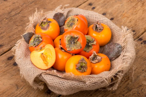 Fresh ripe persimmon on a wooden table - selective focus — Stock Photo, Image