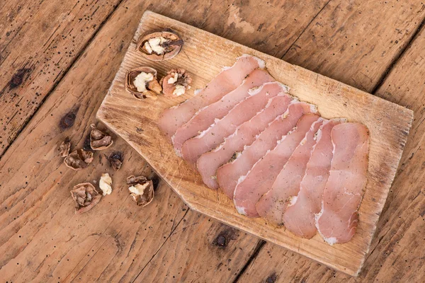 Filetto di maiale essiccato su una tavola rustica di legno grezzo — Foto Stock