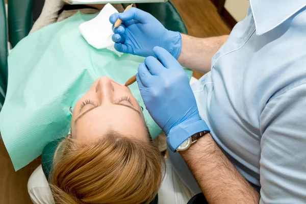 Dentista fazendo um tratamento odontológico em um paciente — Fotografia de Stock