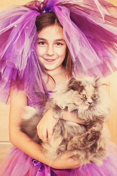 Chica vestida de púrpura sosteniendo al gato en sus manos — Foto de Stock