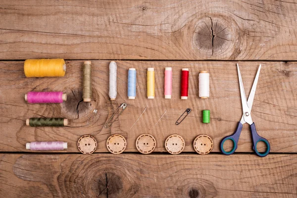 Vue du dessus des accessoires de couture disposés sur une vieille planche vintage — Photo