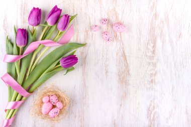 Paskalya yumurtaları ve Beyaz ahşap masa üzerinde çiçekler