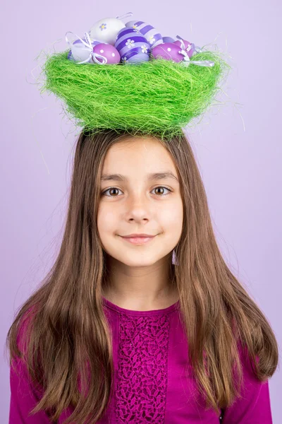 Little girl and nest with Easter eggs over her head — Stock Photo, Image