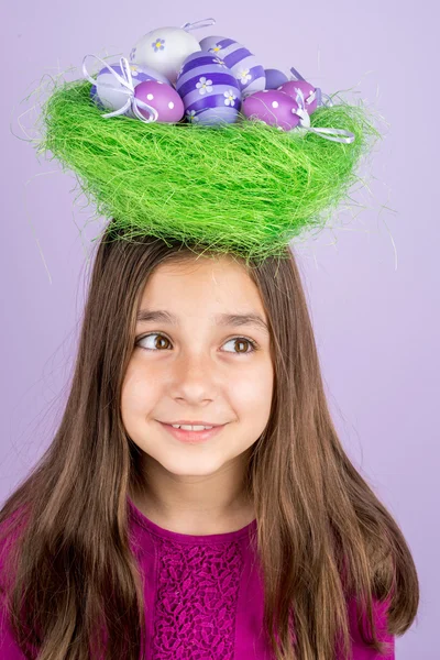 Little girl and nest with Easter eggs over her head — Stock Photo, Image