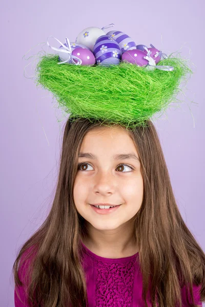 Little girl and nest with Easter eggs over her head — Stock Photo, Image