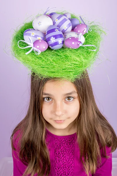 Klein meisje en nest met paaseieren over haar hoofd — Stockfoto