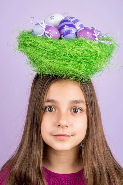 Little girl and nest with Easter eggs over her head — Stock Photo, Image