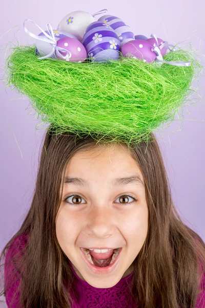 Little girl and nest with Easter eggs over her head — Stock Photo, Image