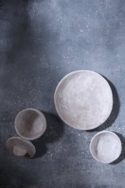 Mavi arka planda boş beyaz kil tabaklar. El yapımı tabak ve kaseler, üst manzara..