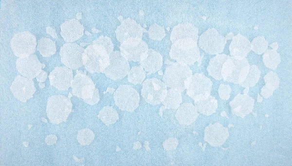 White round plastic foam sheet pieces on blue background. Winter snowfall concept. Torn foam polyethylene transparent pieces as snowflakes.