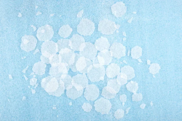 White round plastic foam sheet pieces on blue background. Winter snowfall concept. Torn foam polyethylene transparent pieces as snowflakes.