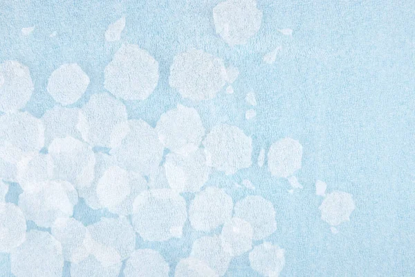 White round plastic foam sheet pieces on blue background. Winter snowfall concept. Torn foam polyethylene transparent pieces as snowflakes.