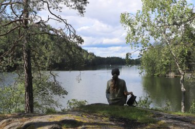 Gölün manzarasının tadını çıkaran bir kadın. Norveç 'te, Oslo Gölü yakınlarındaki ormanda yürüyüş yapan bir kadın..